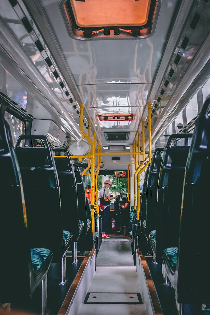 View of a bright and modern public bus interior with passengers standing and sitting, emphasizing public transport.